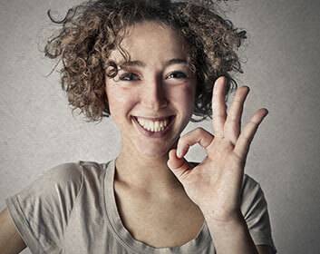 a woman smiling and giving a hand sign